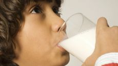 A close-up of a young boy drinking a glass of milk