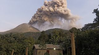 A photo of a volcano spewing ash and smoke in the jungle