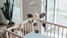 photo of a baby mobile with soft cloud shapes and rain drops hanging above an empty crib