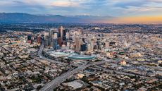 A wide angle photo of downtown Los Angeles showing a sunset and snowy mountains in the background