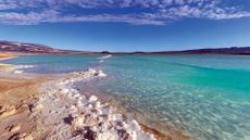 A photo of a desert with a pool of bright blue lithium-rich brine